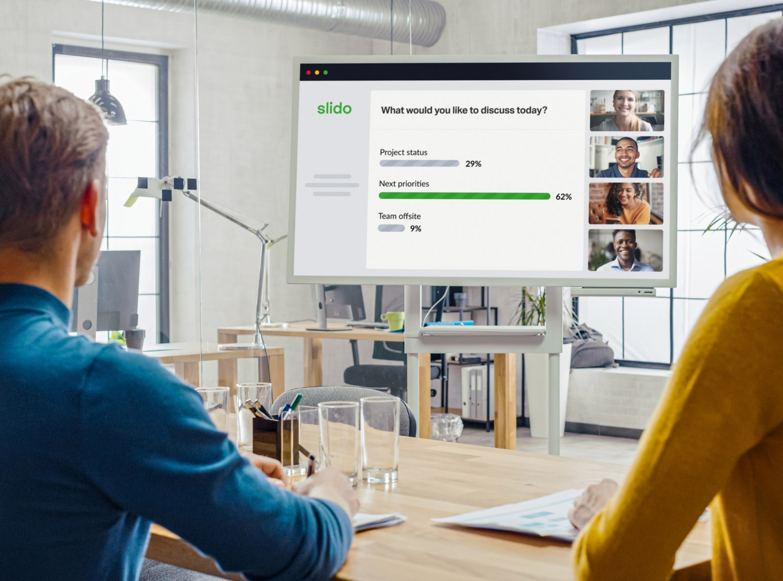 Colleagues looking at a screen while attending a hybrid meeting.